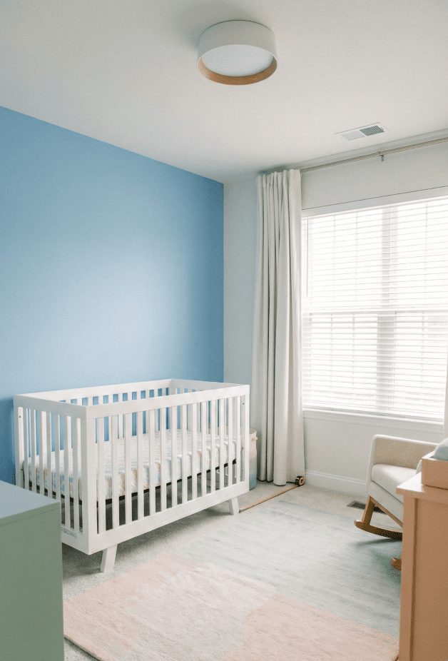 A safe nursery layout showing the crib positioned away from windows and blind cords to prevent strangulation hazards.