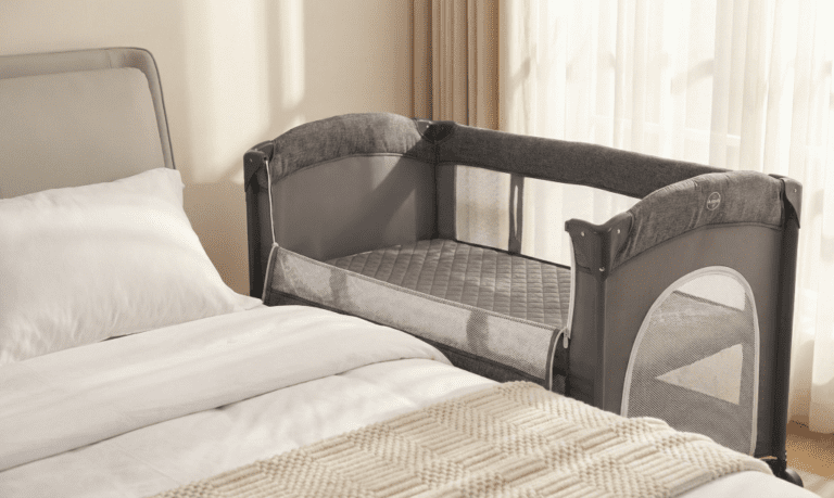 Adovel Bedside Sleeper set up next to an adult bed showing the drop-down side and breathable mesh walls for our Adovel bedside Bassinet Review.