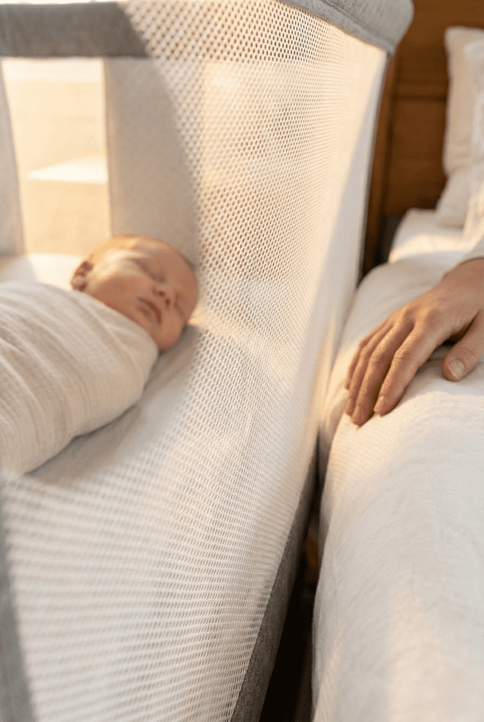 Close-up on the breathable mesh side of the Arm's Reach Clear-Vue bassinet, allowing a clear view of the baby inside from the parent's bed.