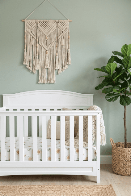 A bohemian-themed nursery featuring the Delta Children Emery 4-in-1 crib, styled with macrame and plants.