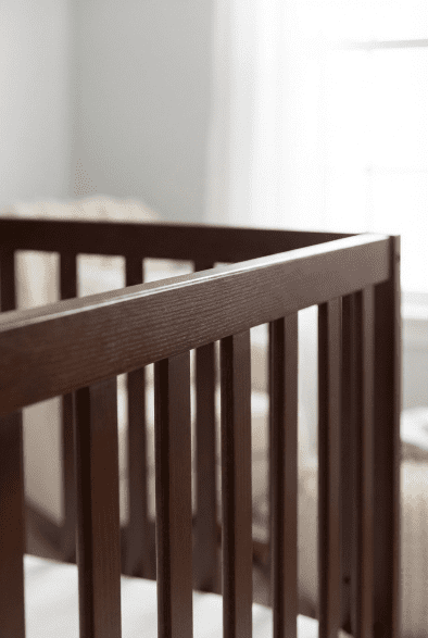 Close-up view of the pine wood grain and non-toxic finish on the rails of the Dream On Me Synergy 5-in-1 crib review.