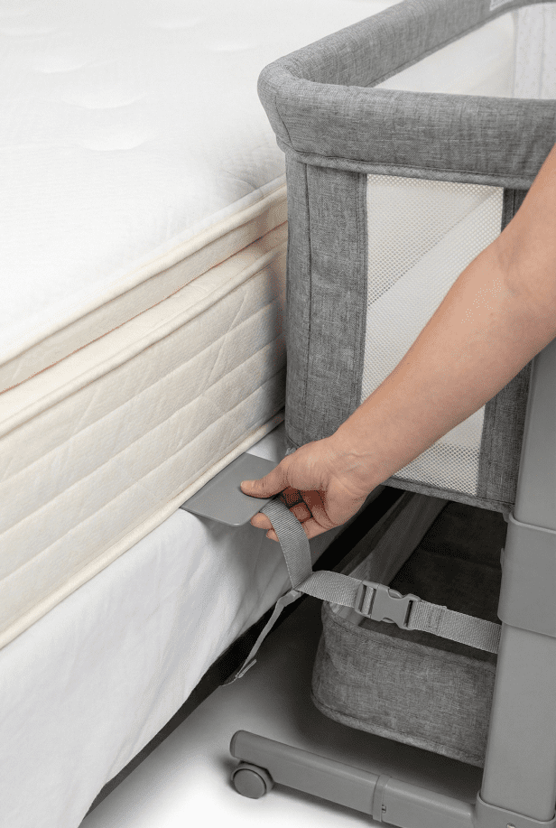 A demonstration of the Arm's Reach anchor plate and strap system being secured under an adult mattress to prevent gaps and ensure safety.