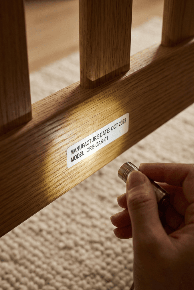 A close-up of a crib safety label showing a 2015 manufacture date, illustrating how to verify if a used crib meets the post-2011 CPSC safety standards.
