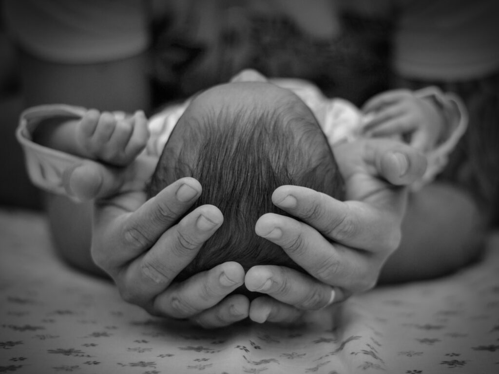 baby sleeps with hands behind head