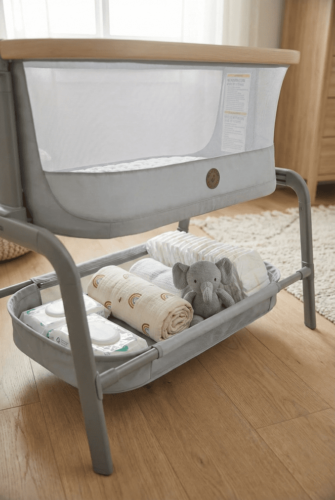 A vertical shot showing the spacious under-bassinet storage basket of the Maxi Cosi Iora filled neatly with baby essentials like diapers and blankets.